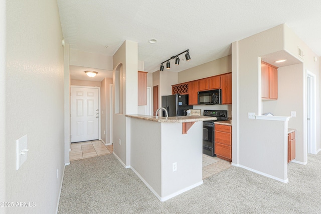 9820 N Central Ave Unit 212, Phoenix, AZ 85020 - kitchen featuring black appliances, light colored carpet, a peninsula, brown cabinets, and a breakfast bar area
