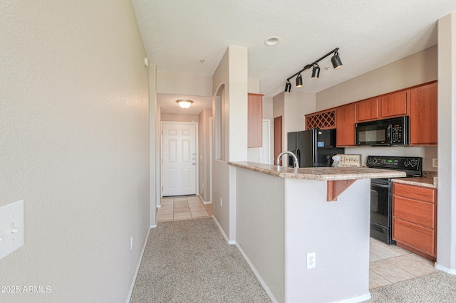 9820 N Central Ave Unit 212, Phoenix, AZ 85020 - kitchen with black appliances, brown cabinetry, light carpet, a breakfast bar, and a peninsula