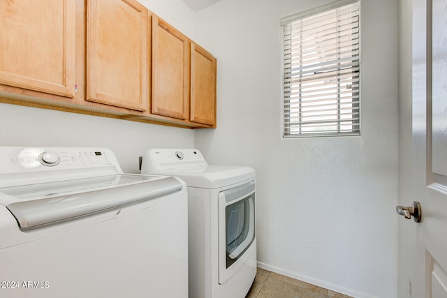 clothes washing area with washing machine and clothes dryer, cabinets, and light tile patterned floors