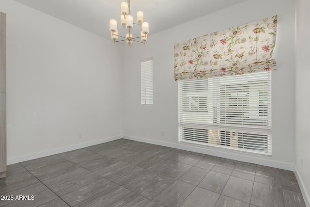 spare room featuring baseboards and an inviting chandelier