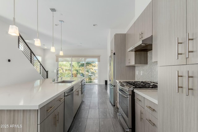 kitchen with under cabinet range hood, stainless steel appliances, a sink, light countertops, and tasteful backsplash