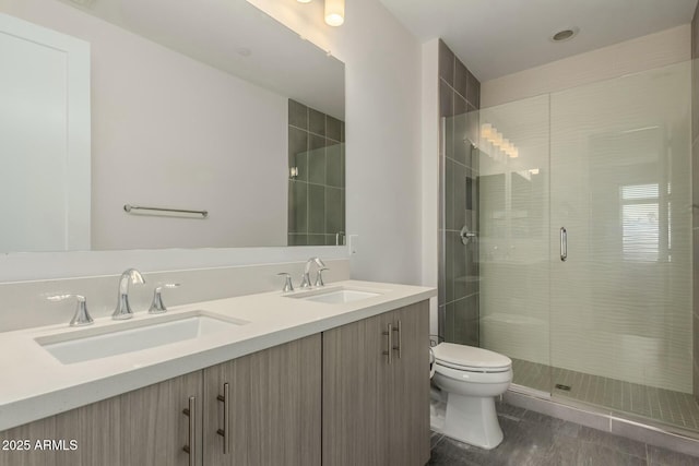 bathroom featuring a sink, a shower stall, toilet, and double vanity