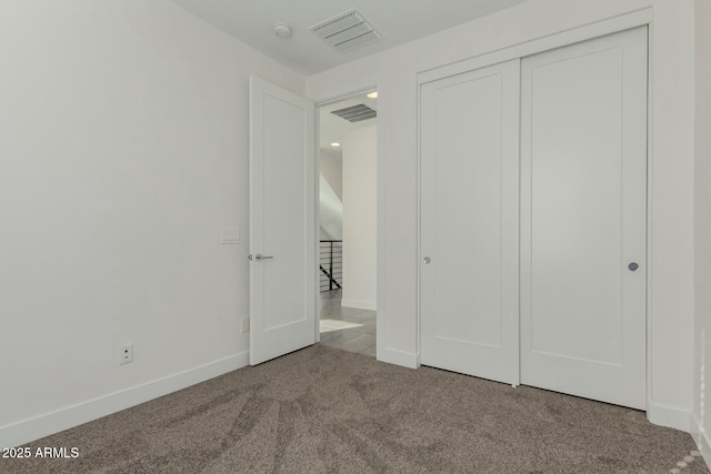 unfurnished bedroom featuring carpet floors, baseboards, visible vents, and a closet