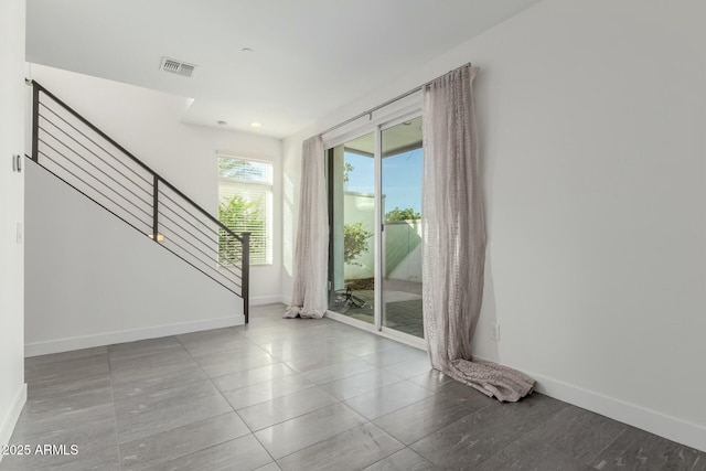 unfurnished room with visible vents, stairway, and baseboards