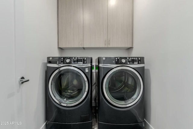 washroom with cabinet space, washer and clothes dryer, and baseboards