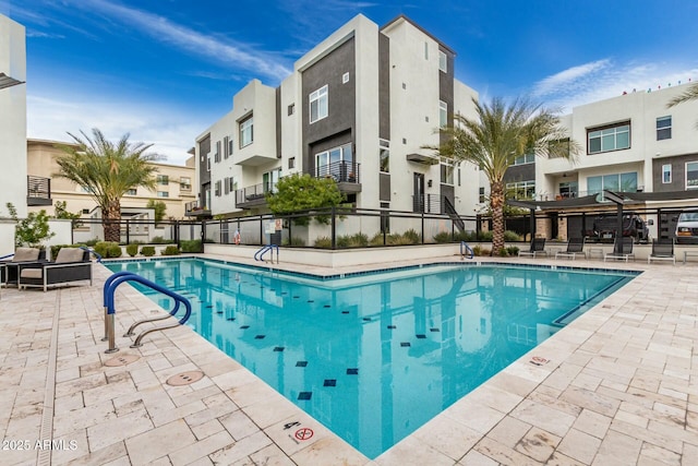 community pool featuring a residential view, a patio area, and fence