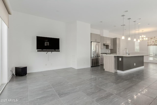 kitchen featuring modern cabinets, open floor plan, light countertops, stainless steel refrigerator with ice dispenser, and a sink