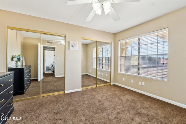 unfurnished bedroom with carpet floors, baseboards, multiple closets, and visible vents