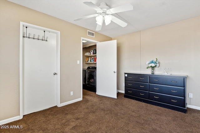 unfurnished bedroom with visible vents, dark colored carpet, baseboards, ceiling fan, and washing machine and clothes dryer