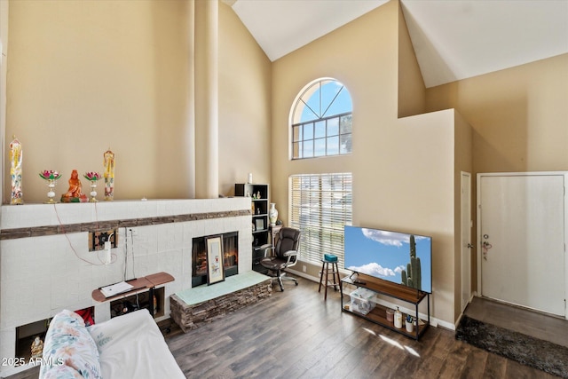 living room with a glass covered fireplace, high vaulted ceiling, baseboards, and wood finished floors