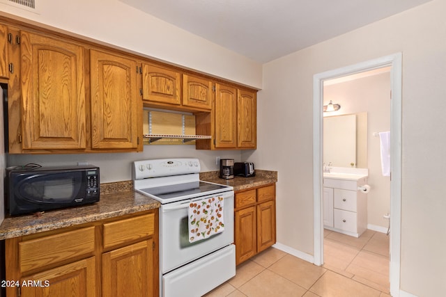 kitchen featuring light tile patterned flooring, dark stone countertops, and electric range