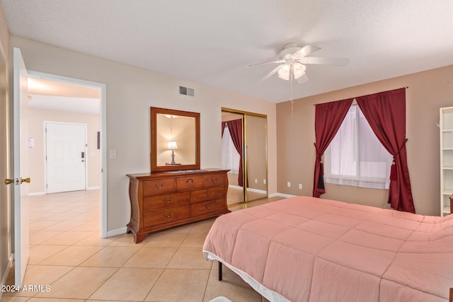 bedroom featuring light tile patterned flooring, ceiling fan, a textured ceiling, and a closet