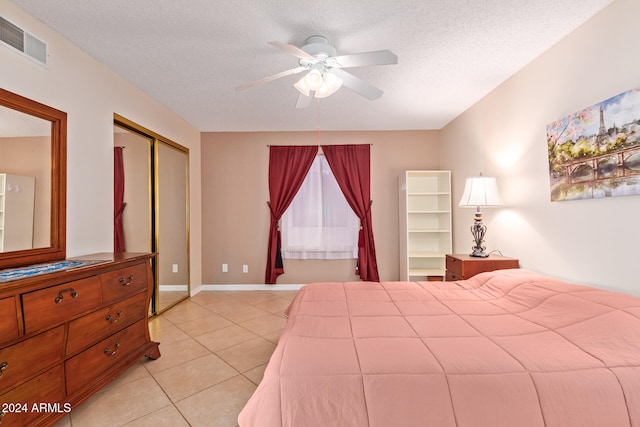 tiled bedroom featuring a closet, a textured ceiling, and ceiling fan