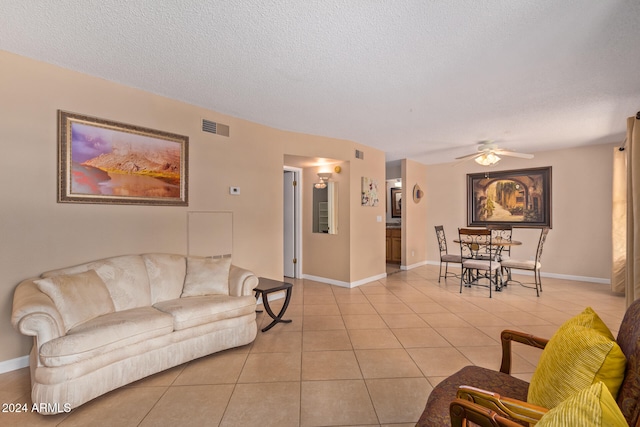 tiled living room with a textured ceiling and ceiling fan