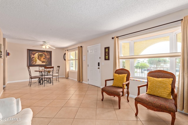 living room featuring ceiling fan, plenty of natural light, light tile patterned floors, and a textured ceiling