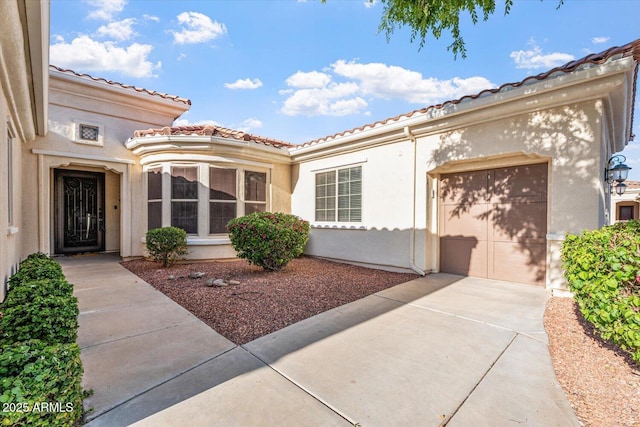 12820 W La Vina Dr, Sun City West, AZ 85375 - doorway to property with concrete driveway, a tile roof, a garage, and stucco siding