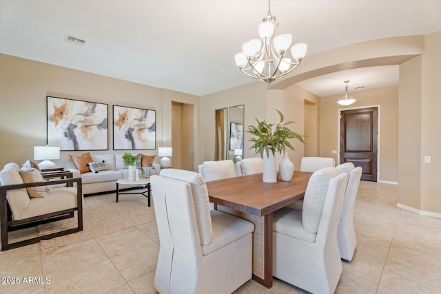 12820 W La Vina Dr, Sun City West, AZ 85375 - dining area featuring arched walkways, baseboards, visible vents, a notable chandelier, and light tile patterned floors