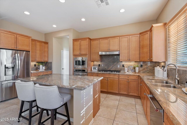 12820 W La Vina Dr, Sun City West, AZ 85375 - kitchen with stainless steel appliances, visible vents, a sink, decorative backsplash, and a breakfast bar area