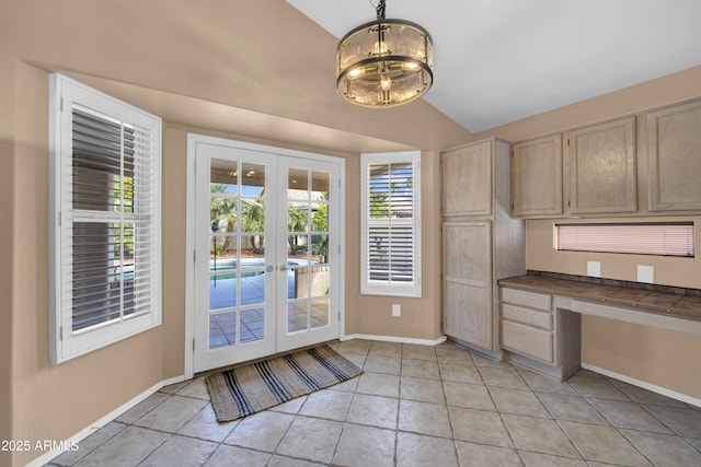 doorway to outside with vaulted ceiling, light tile patterned flooring, and french doors