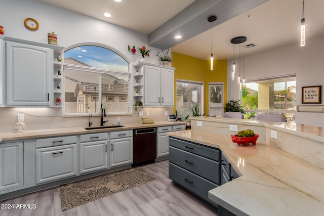 kitchen with pendant lighting, backsplash, white cabinets, sink, and light stone countertops