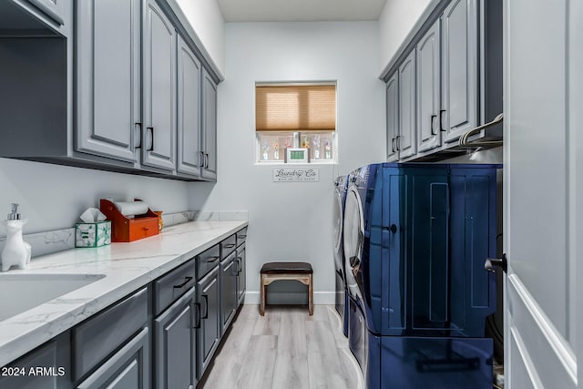 laundry area featuring washing machine and dryer, light hardwood / wood-style flooring, cabinets, and sink