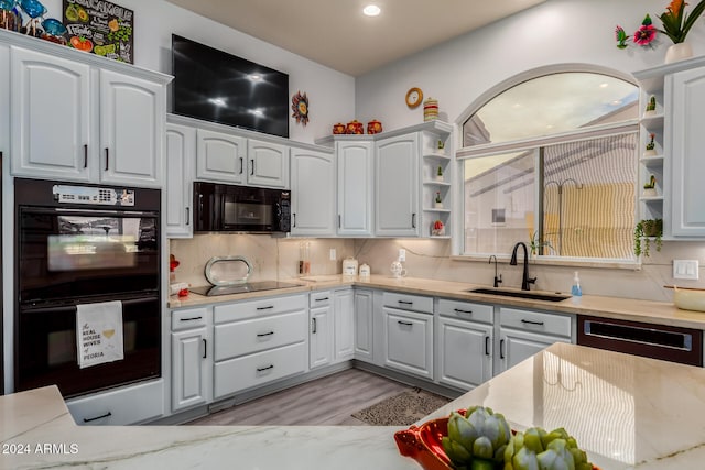 kitchen featuring sink, light hardwood / wood-style flooring, white cabinetry, and black appliances