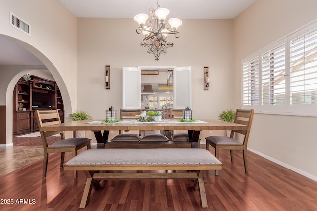 dining area featuring baseboards, wood finished floors, visible vents, and a chandelier