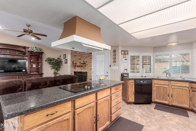 kitchen with a sink, black appliances, custom range hood, open floor plan, and a large fireplace