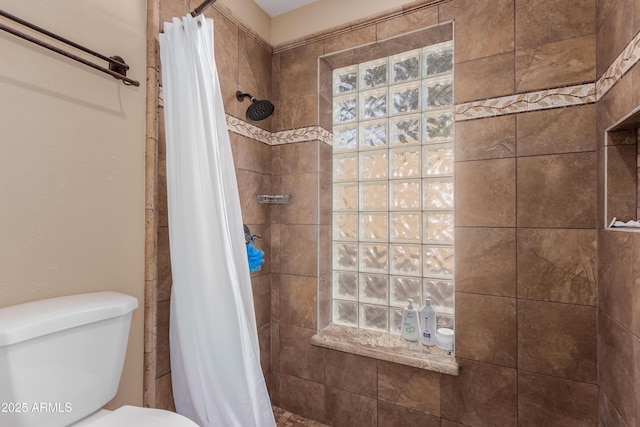 bathroom with toilet and a tile shower