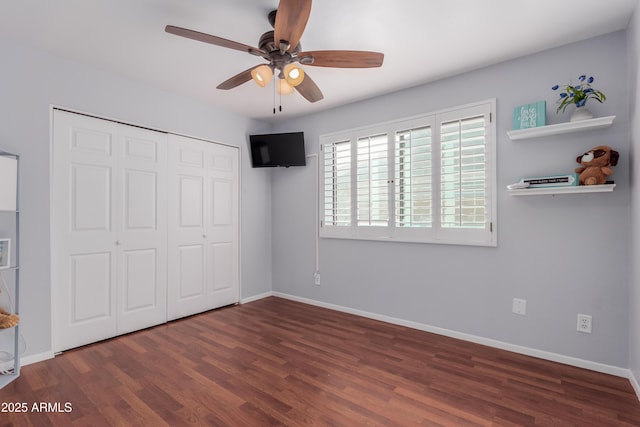 unfurnished bedroom featuring a closet, a ceiling fan, baseboards, and wood finished floors