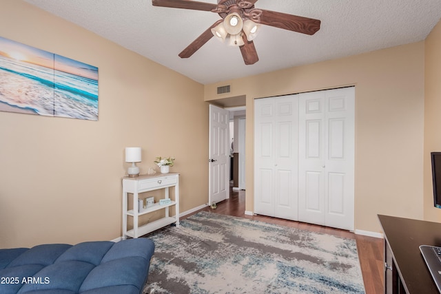 sitting room with wood finished floors, baseboards, visible vents, ceiling fan, and a textured ceiling