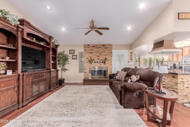 living room with wood finished floors, a ceiling fan, recessed lighting, vaulted ceiling, and a large fireplace