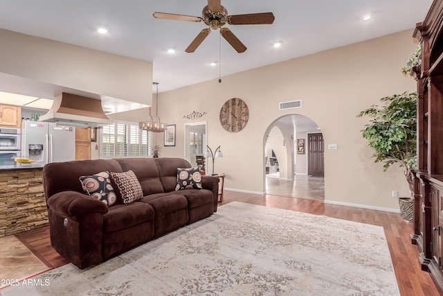 living area featuring visible vents, ceiling fan with notable chandelier, wood finished floors, recessed lighting, and arched walkways