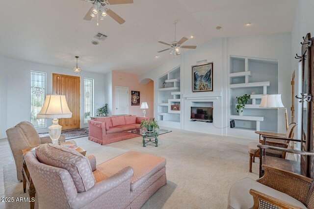 16507 E Trevino Dr, Fountain Hills, AZ 85268 - carpeted living room with vaulted ceiling, built in shelves, visible vents, a ceiling fan, and a glass covered fireplace
