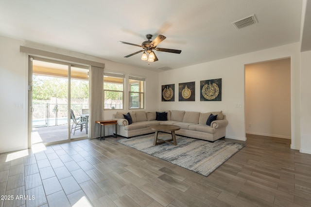 living room with baseboards, ceiling fan, wood finished floors, and visible vents