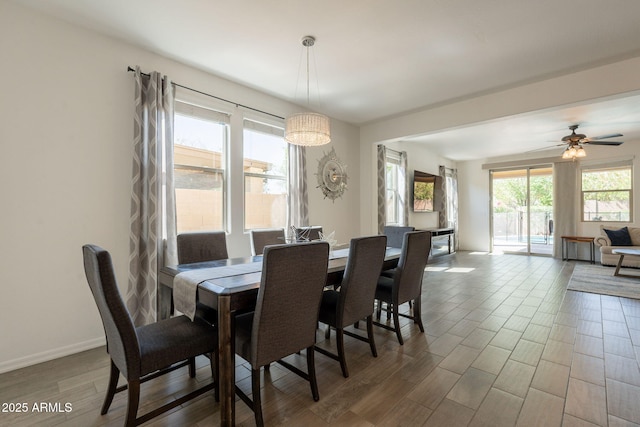 dining space with a ceiling fan, baseboards, and wood finished floors