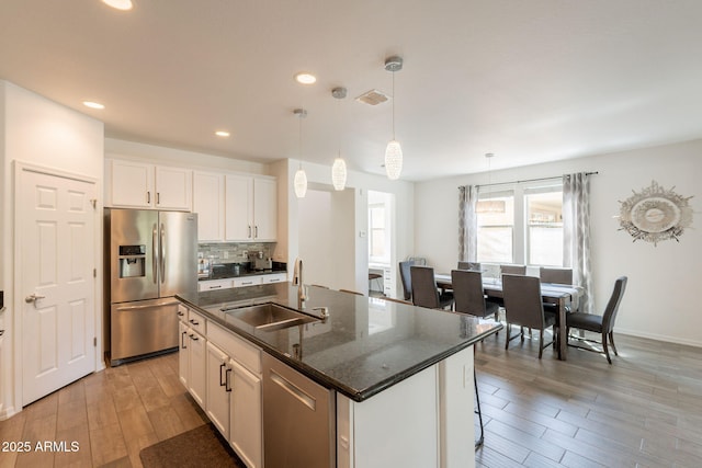 kitchen featuring backsplash, a sink, light wood finished floors, stainless steel appliances, and recessed lighting