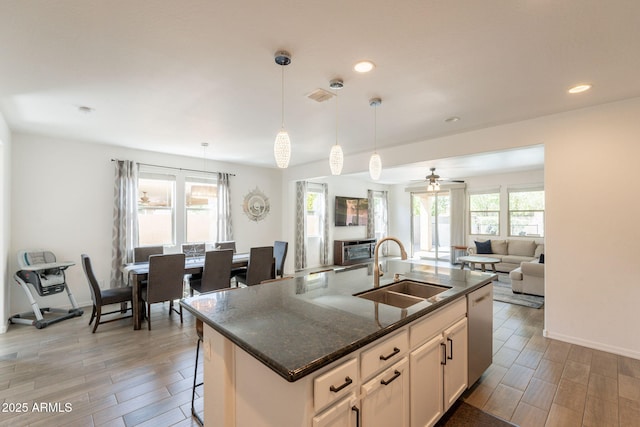 kitchen featuring stainless steel dishwasher, a sink, open floor plan, and wood tiled floor
