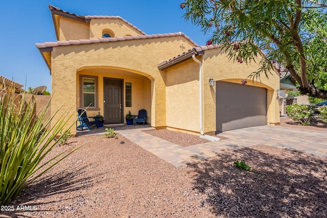 mediterranean / spanish-style home featuring fence, a tile roof, a garage, stucco siding, and driveway