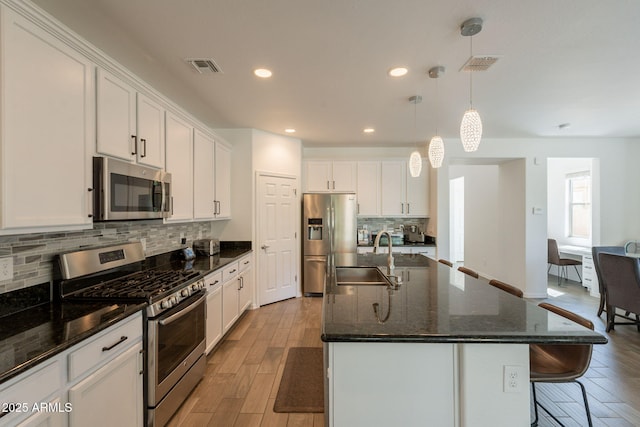 kitchen featuring white cabinets, appliances with stainless steel finishes, a sink, and wood finished floors