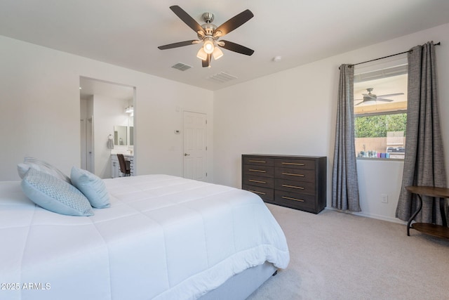 bedroom with visible vents, ceiling fan, ensuite bath, and light colored carpet