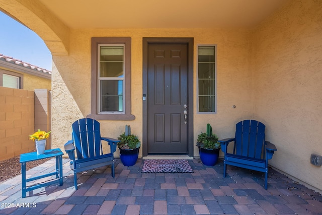 doorway to property featuring a patio, fence, and stucco siding