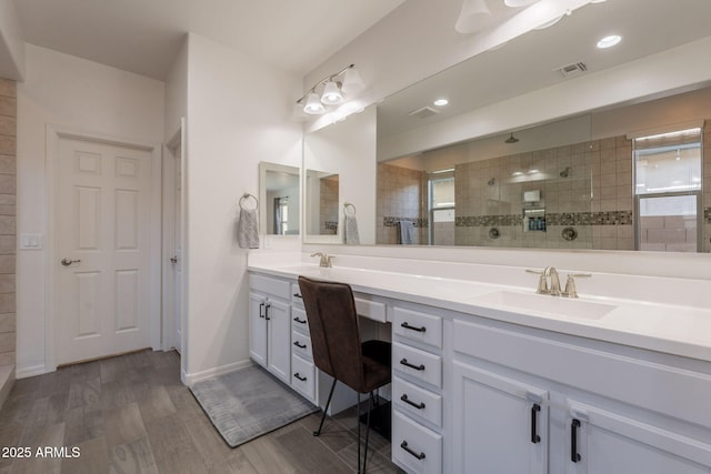 full bathroom with double vanity, visible vents, wood finished floors, a sink, and a walk in shower