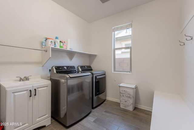 washroom with washing machine and dryer, light wood-style floors, baseboards, a sink, and cabinet space