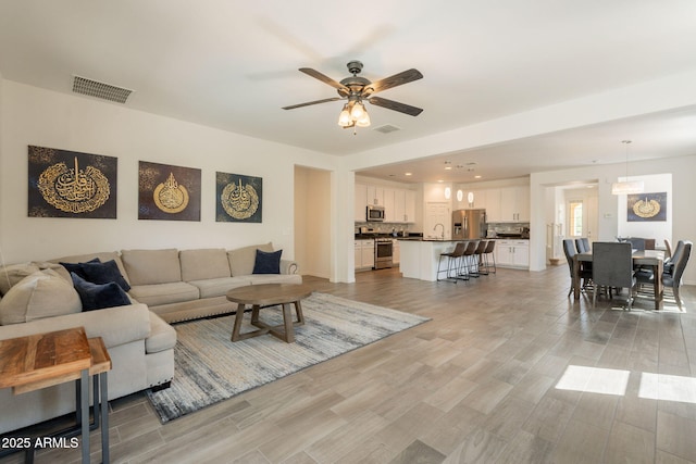 living area featuring visible vents, a ceiling fan, and light wood-type flooring