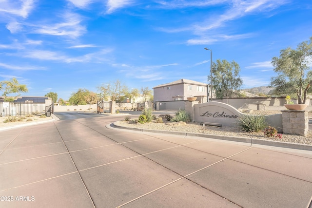 view of street featuring street lighting, a gated entry, and curbs