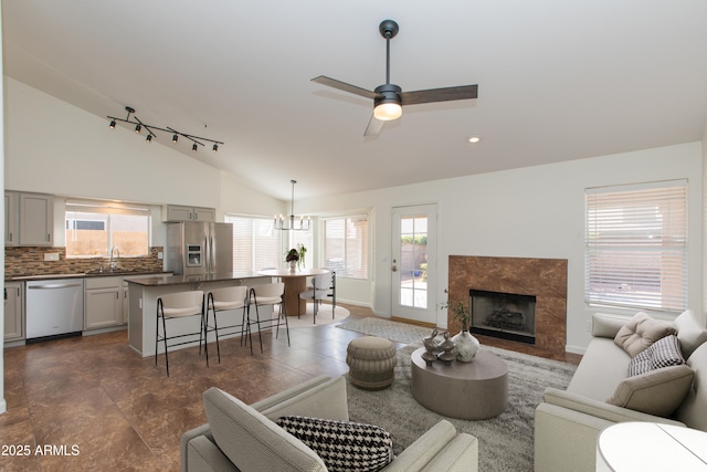 living area featuring recessed lighting, a premium fireplace, a ceiling fan, vaulted ceiling, and baseboards