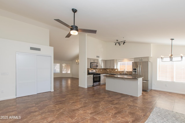 kitchen with gray cabinetry, stainless steel appliances, a center island, dark countertops, and pendant lighting