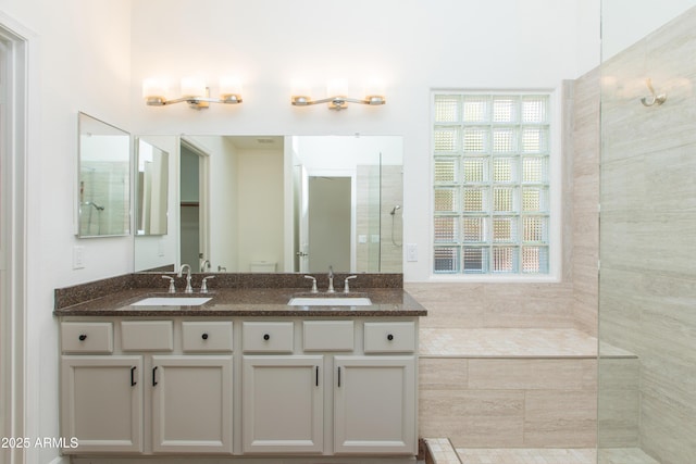 full bath with double vanity, a wealth of natural light, and a sink