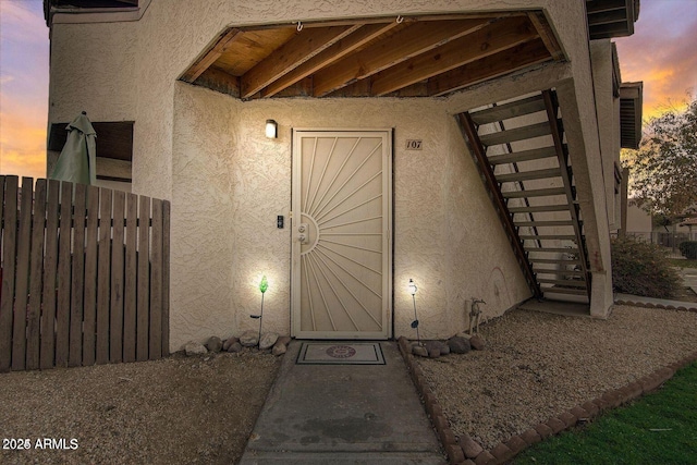 exterior entry at dusk with fence and stucco siding